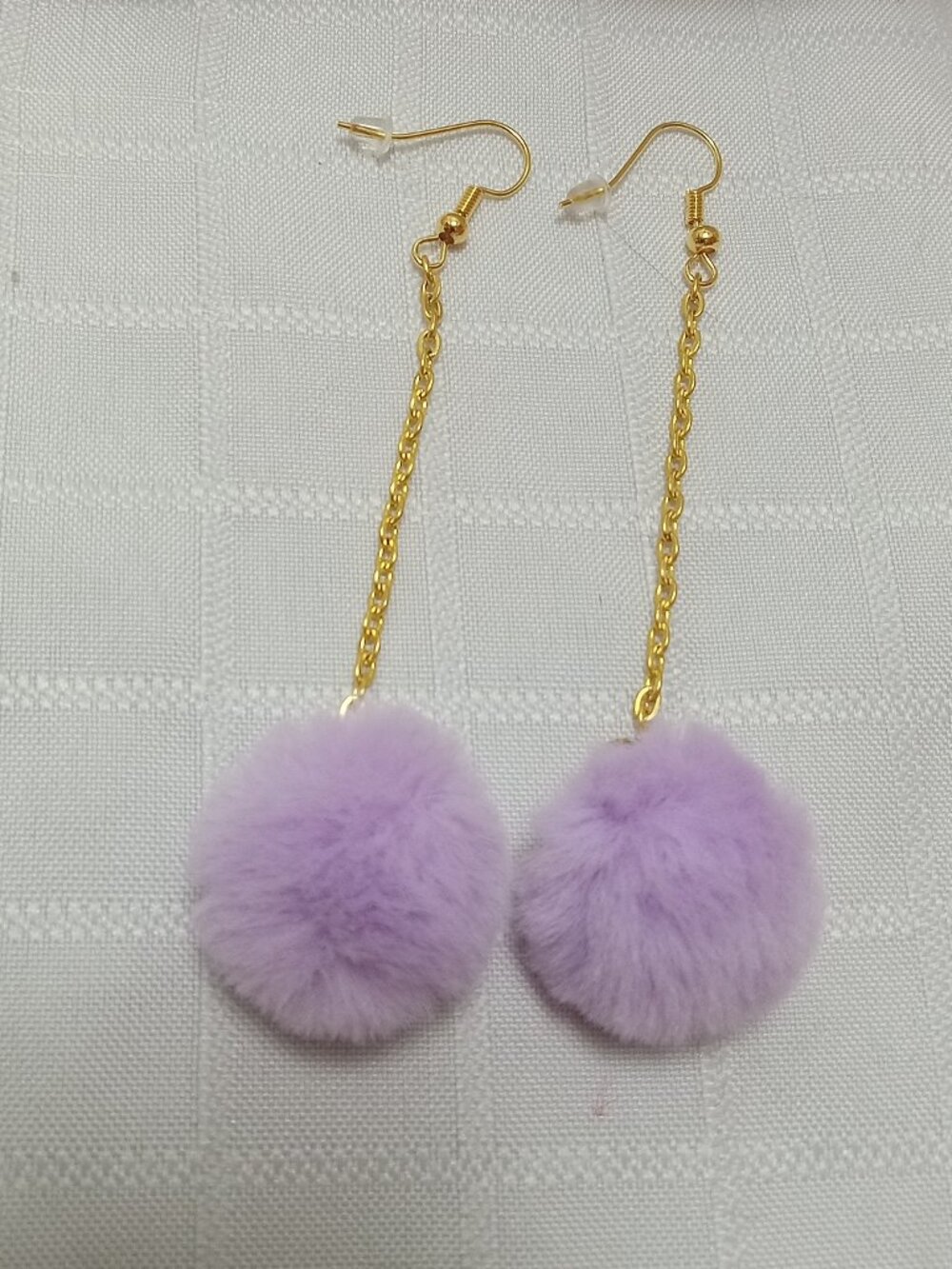 Handmade earrings with small pom-poms and gold-colored accent hooks and chains